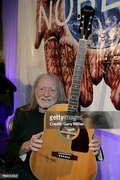 Musician/vocalist Willie Nelson signs an Epiphone guitar for a $20,000 donor at the Nobelity Project's dinner honoring Willie Nelson with the "Feed...
