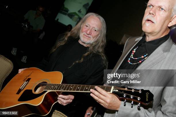 Musician/vocalist Willie Nelson signs an Epiphone guitar for a $20,000 donor at the Nobelity Project's dinner honoring Willie Nelson with the "Feed...