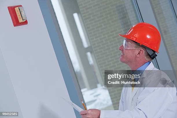 engineer inspecting fire alarm in a building - beschützer stock-fotos und bilder