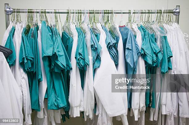 doctor's uniforms hanging on a clothes rack - medical scrubs hanger stock pictures, royalty-free photos & images