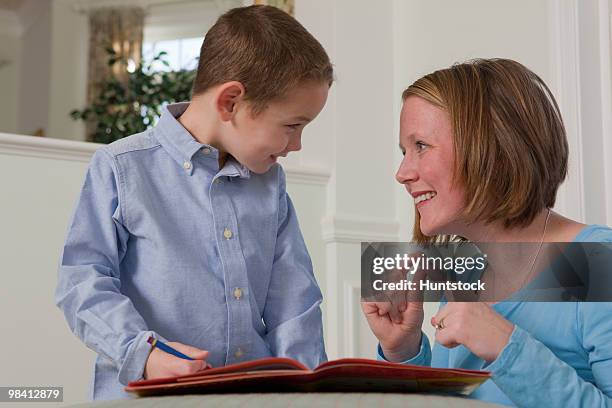 woman signing the word 'word' in american sign language while teaching her son - american sign language fotografías e imágenes de stock