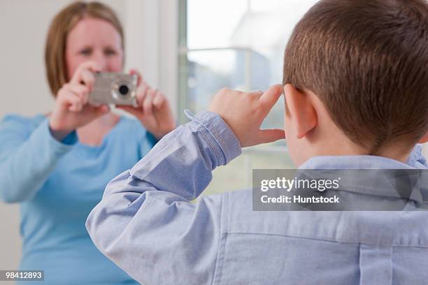 boy signing the word 'picture' in american sign language while his mother taking a picture of him with a digital camera - depth of field togetherness looking at the camera ストックフォトと画像