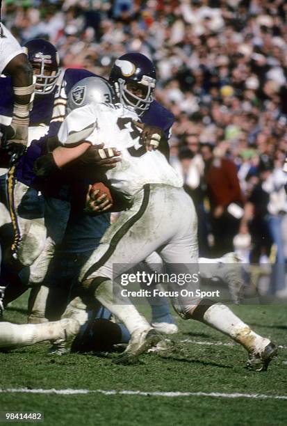 Defensive tackle Alan Page of the Minnesota Vikings wraps up running back Mark van Eeghen of the Oakland Raiders during Super Bowl XI on January 9,...