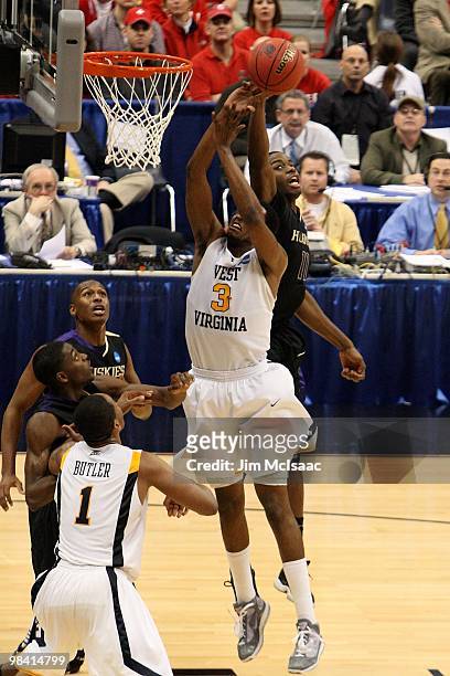 Matthew Bryan-Amaning of the Washington Huskies blocks a shot attempt by Devin Ebanks of the West Virginia Mountaineers during the east regional...