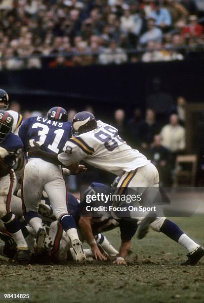 1970s: Defensive Tackle Alan Page of the Minnesota Vikings hits running back Charlie Evans of the New York Giants circa early 1970's during an NFL...