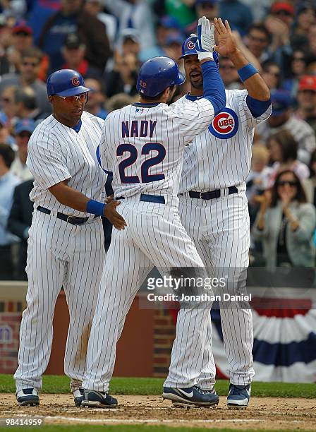 Xavier Nady of the Chicago Cubs is greeted by teammates Marlon Byrd and Derrek Lee after hitting a three-run home run in the fourth inning against...