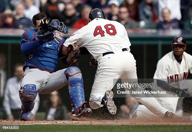 Taylor Teagarden of the Texas Rangers tags out Travis Hafner of the Cleveland Indians while colliding with him at home plate during the Opening Day...