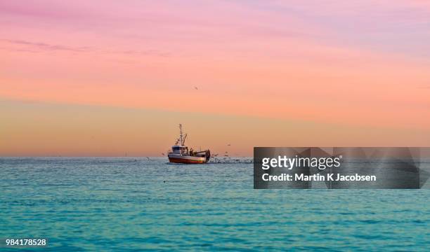 a boat out at sea during sunset. - bateau de pêche photos et images de collection