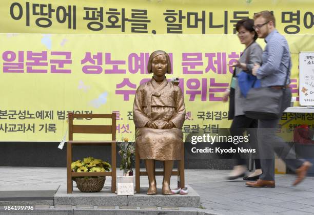 People walk past a statue symbolizing so-called comfort women near the Japanese Embassy in Seoul on June 19, 2018. ==Kyodo