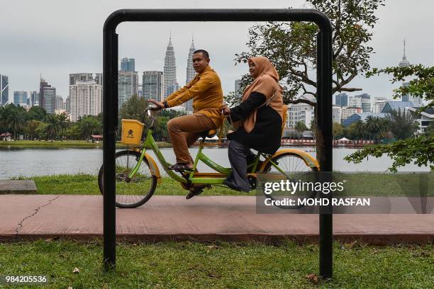 Couple rides a tandem at a park in Kuala Lumpur on June 26 as the city's iconic landmark Petronas Twin Towers dominate the skyline.