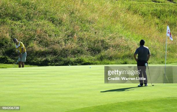 Felipe Aguilar of Chile watches his caddie chip onto the 18th green plays a practice round ahead of the HNA Open de France at Le Golf National on...