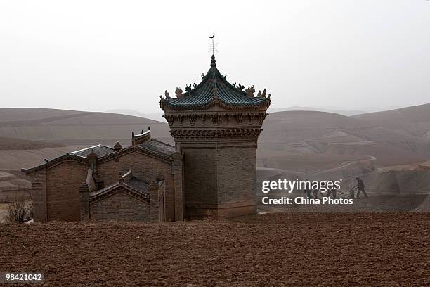 Couple sows seeds in a field near the Muslim dome-shaped tombs on March 14, 2010 in Xihaigu, Tongxin County of Ningxia Hui Autonomous Region, north...