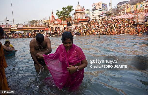 Hindu couple holds hands after bathing in the river Ganges as deoveets crowd both banks during the Kumbh Mela festival in Haridwar on April 13, 2010....