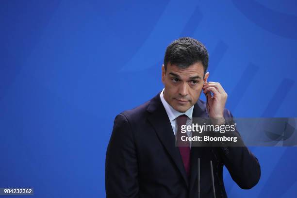 Pedro Sanchez, Spain's prime minister, adjusts his earpiece during a news conference with Angela Merkel, Germany's chancellor, in the Chancellery in...