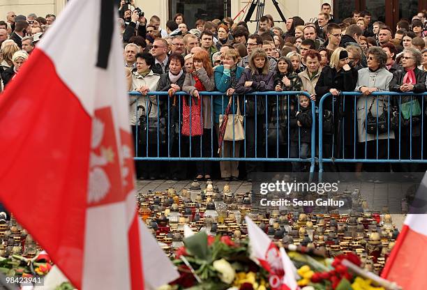 Mourners stand outside the Presidential Palace over candles, flags and flowers left in memory of late Polish President Lech Kaczynski on April 13,...