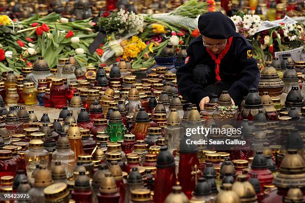 Polish boy scout arranges candles left by mourners outside the Presidential Palace in memory of late Polish President Lech Kaczynski on April 13,...