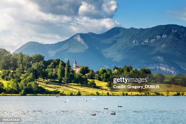 paisaje francés con pequeño campanario iglesia a lo largo de río ródano y las montañas grand colombier bugey alpes en verano en auvernia-rhone-alpes - ain fotografías e imágenes de stock