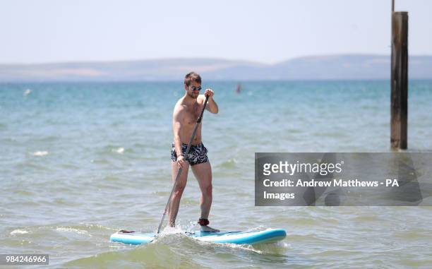 Chris Bryant from Basingstoke paddle boards at Boscombe Beach in Dorset, as temperatures are predicted to increase this week.
