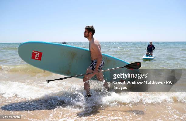 Chris Bryant from Basingstoke leaves the water after paddle boarding at Boscombe Beach in Dorset, as temperatures are predicted to increase this week.