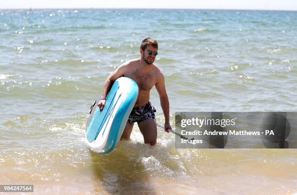 Chris Bryant from Basingstoke leaves the water after paddle boarding at Boscombe Beach in Dorset, as temperatures are predicted to increase this week.