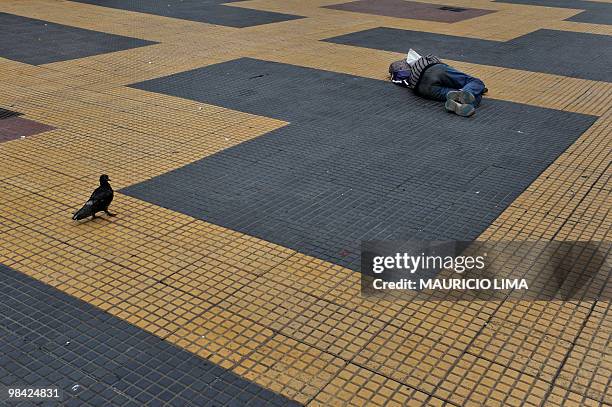 Dove approaches a homeless man as he sleeps on the ground at the 'Praca da Republica' area, in downtown Sao Paulo, Brazil, on October 15, 2009. AFP...