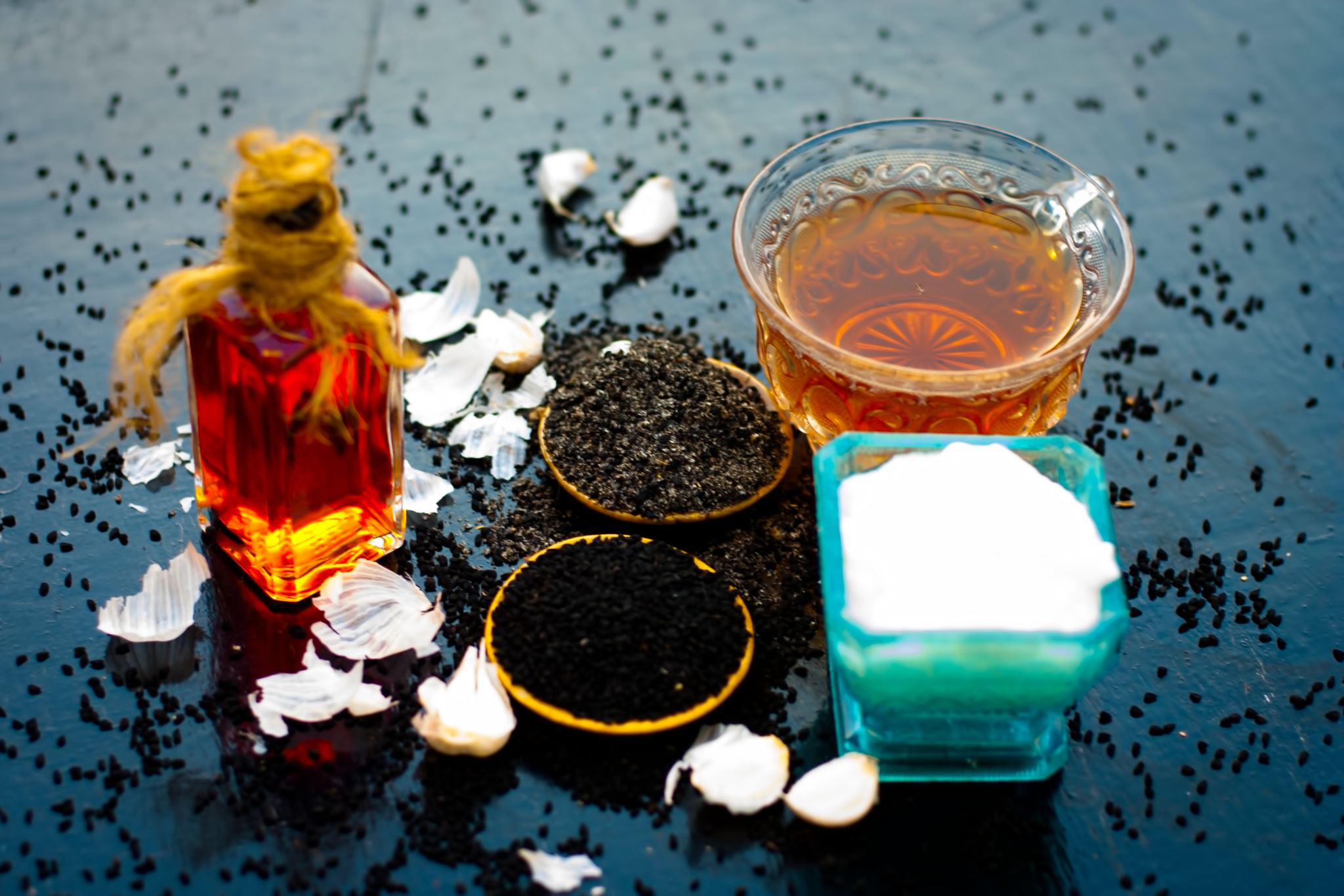 Close up of kalonji with curd or youghurt on wooden surface with black tea and its extracted oil and some garlic cloves reduces chances of cancer, ulcers and diabetes. Close up of kalonji with curd or youghurt on wooden surface with black tea and its extracted oil and some garlic cloves reduces chances of cancer, ulcers and diabetes.