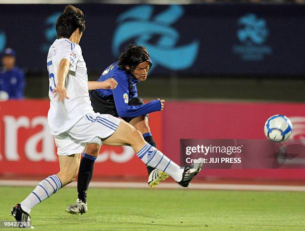 Japan's Gamba Osaka midfielder Takashi Usami shoots the ball while South Korea's Suwon Bluewings defender Li Wei-Feng attempts to block him during...