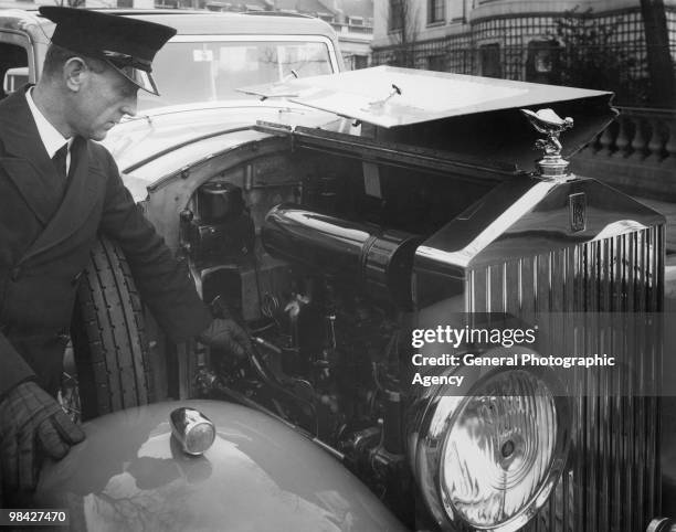 Chauffeur tinkers with the engine of a Rolls Royce, circa 1940.