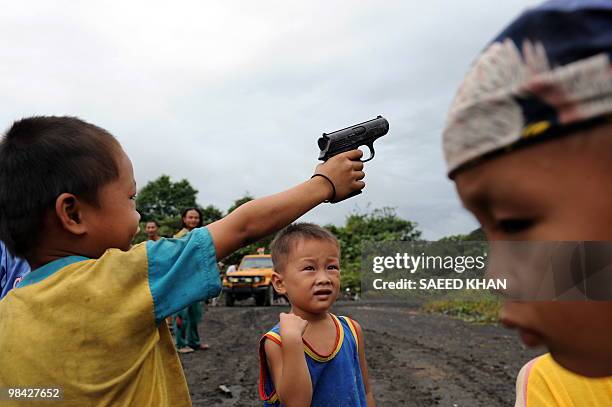 Malaysia-Penan-nomads-environment" by Sarah Stewart A child of the Penan tribe waves his toy pistol while playing with other children outside his...