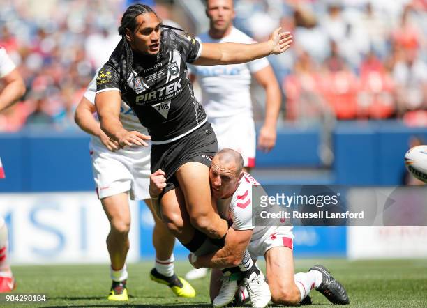 Martin Taupau of New Zealand tosses the ball to a teammate as he's tackled by James Roby of England during the second half of a Rugby League Test...