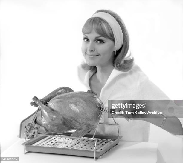 Portrait of a smiling woman as she posies with a rotisserie chicken, 1966.
