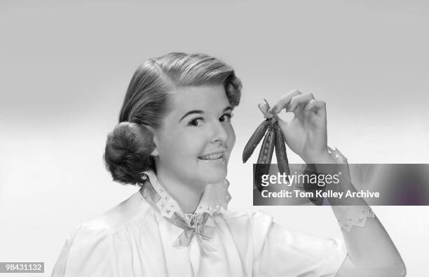 Portrait of a smiling women as she holds aloft several pea pods, 1948.