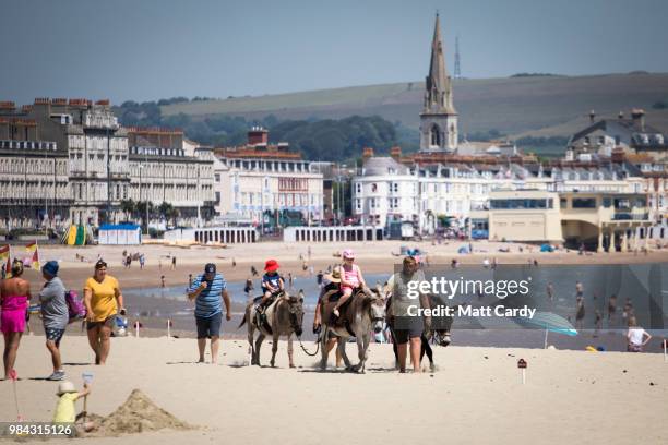 People take donkey rides on Weymouth seafront on June 26, 2018 in Dorset, England. Parts of the UK are currently basking in heatwave temperatures...