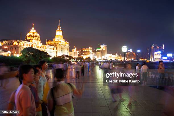 Tourists on the Bund at sunset look out over the cityscape and skyline of Pudong Financial District over Huang Pu River in Shanghai, China. Every day...