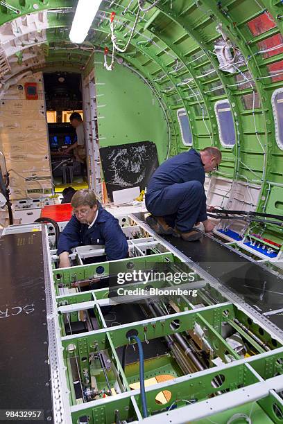 Workers install wire and cables inside the fuselage of a Bombardier Q400 NextGen turboprop airliner, in one of the hangars at the Bombardier...