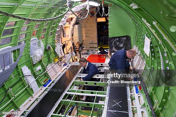 Workers install wire and cables inside the fuselage of a Bombardier Q400 NextGen turboprop airliner, in one of the hangars at the Bombardier...