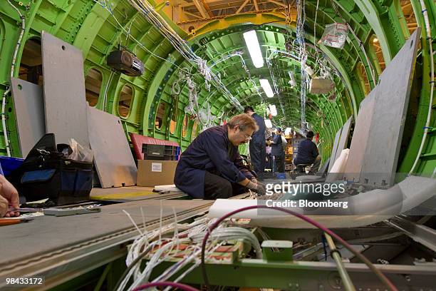 Workers install wire and cables inside the fuselage of a Bombardier Q400 NextGen turboprop airliner, in one of the hangars at the Bombardier...
