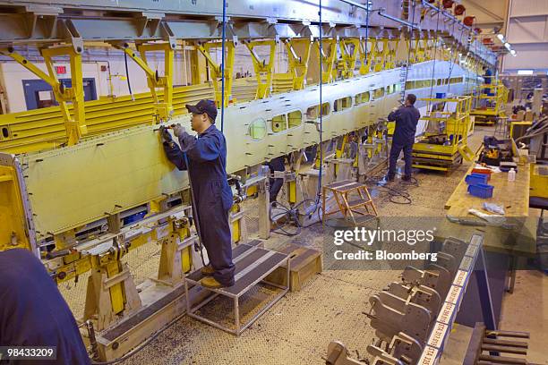 James Culala, center, works on a wing for a Bombardier Q400 NextGen turboprop airliner, in one of the hangars at the Bombardier Aerospace plant at...