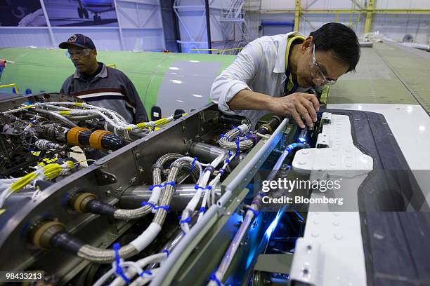 Rueben Tumanguil uses a flashlight inspect a newly installed engine on a Bombardier Q400 NextGen turboprop airliner, in one of the hangars at the...