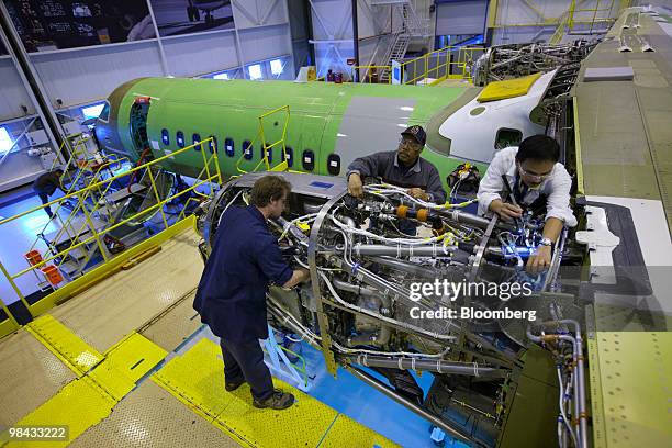 Workers inspect a newly-installed engine on a Bombardier Q400 NextGen turboprop airliner, in one of the hangars at the Bombardier Aerospace plant at...