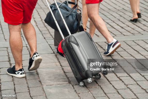 business men in shorts walking with suitcase on cobbled pavement - wheeled luggage stock pictures, royalty-free photos & images