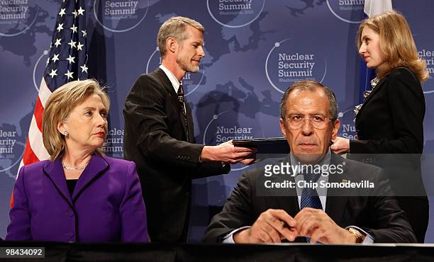 Secretary of State Hillary Rodham Clinton and Russian Foreign Minister Sergey Lavrov wait as aides exchange signed copies of an agreement on...
