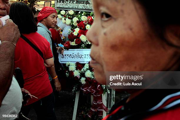 Anti-government 'Red Shirt' protesters walk infront of the caskets at the memorial site for the victims of the fierce street battles between...