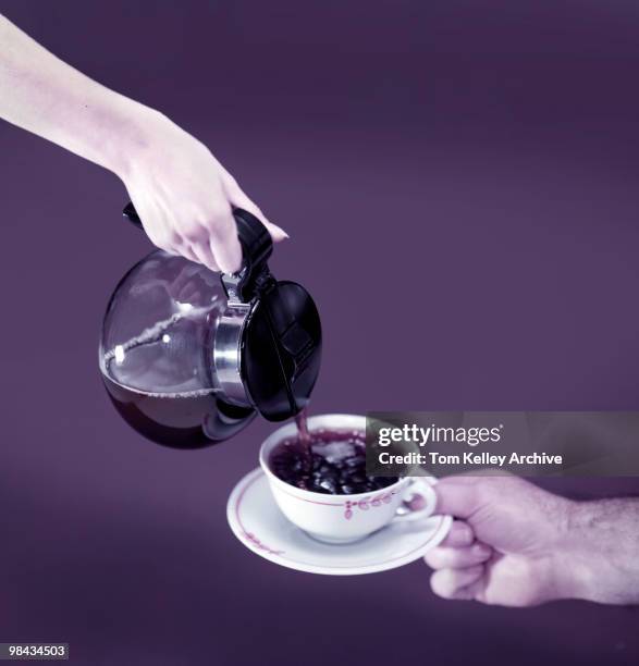 View of a woman's hand as it pour coffee from a carafe into a cup on a saucer held by a man's hand, 1952.