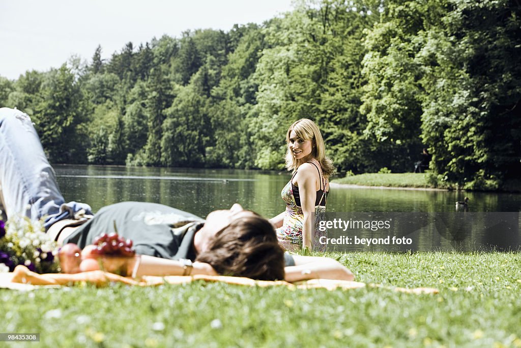 Young woman watching her boyfriend sleeping in grass