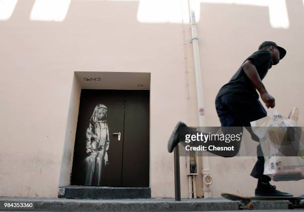 Man walks past a recent artwork attributed to street artist Banksy on June 26, 2018 in Paris, France. Yesterday a new artwork attributed to street...