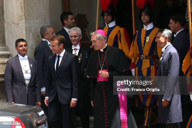 French President Emmanuel Macron, flanked by Prefect of the Pontifical House Georg Ganswein , leaves the Apostolic Palace at the end of an audience...