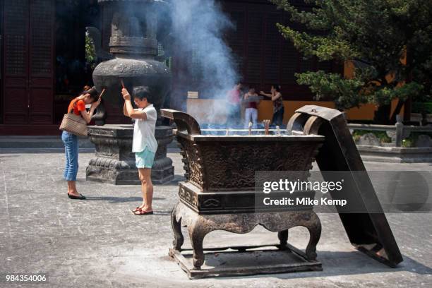 Shanghainese people burn incense during daily prayer sessions at the Longhua Temple in the south of Shanghai, China. This is a working Buddhist...