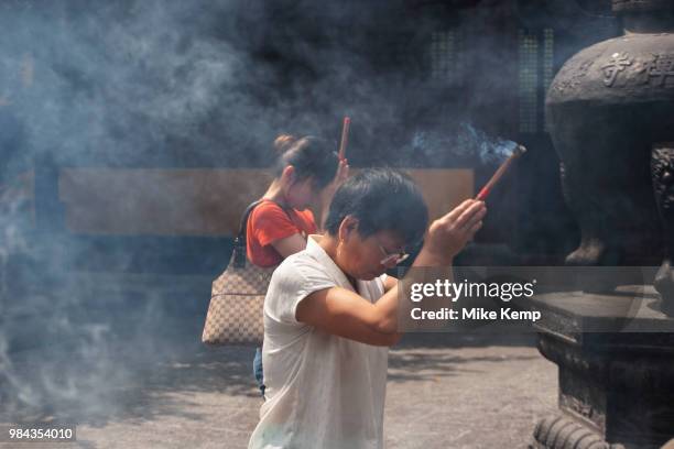 Shanghainese people burn incense during daily prayer sessions at the Longhua Temple in the south of Shanghai, China. This is a working Buddhist...