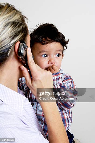 portrait of toddler held by mother talking on mobile phone - international mother language day stock-fotos und bilder